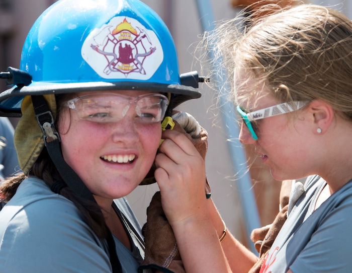 (Rick Egan  |  The Salt Lake Tribune)  Clarissa gets some assistance from Victoria, as she removes her helmet, after the firefighter skills relay, while attending Camp Fury.  A dozen Utah Girl Scouts participated in a 3-day camp led by female firefighters. Camp Fury Utah was developed in partnership with the Girl Scouts and local fire and police departments, designed to expose teen girls to careers in public safety and other non-traditional jobs. Saturday, August 5, 2017.


