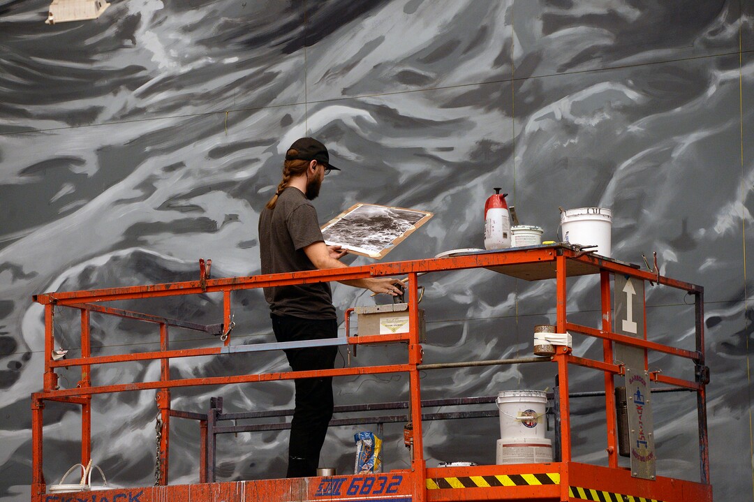 (Al Hartmann  |  The Salt Lake Tribune) 	Artist Rob Asay works on painting the giant stage backdrop of ocean waves from a lift in early December for Utah Opera's new production of "Moby-Dick," which will play in January 2018. 