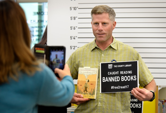 (Scott Sommerdorf   |  The Salt Lake Tribune)   
Carvel Harward has his photo made in front of the improvised lineup background at the Smith Branch of the County Library. The public was invited to bring their favorite banned book to the Smith branch and participate in a Facebook live event where they would all read from their banned books, simultaneously, for approximately three minutes in celebration of our intellectual freedom, Sunday, September 24, 2017.