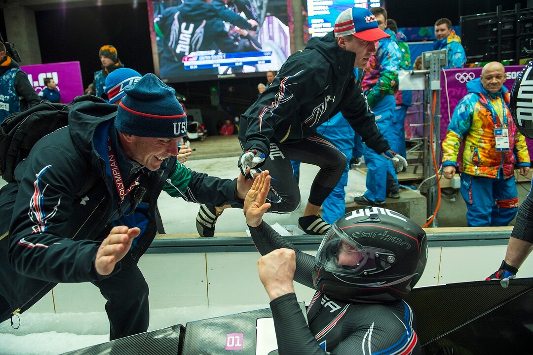 KRASNAYA POLYANA, RUSSIA  - JANUARY 17:USA bobsled Head Coach Brian Shimer, left, congratulates pilot Steven Holcomb, as Christopher Fogt goes to celebrate with brakeman Steven Langton, not pictured, after competing in the men's two-man bobsled at Sanki Sliding Center during the 2014 Sochi Olympics Monday February 17, 2014. USA-1 with Steven Holcomb, of Park City, Utah, and Steve Langton, of Melrose, Mass., won the bronze medal with a time of 3:46.27.(Photo by Chris Detrick/The Salt Lake Tribune)