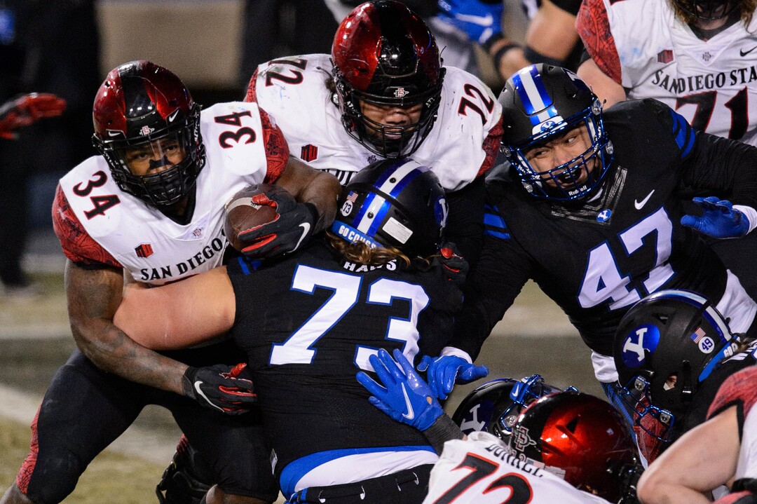 (Trent Nelson  |  The Salt Lake Tribune) Brigham Young Cougars defensive lineman Caden Haws (73) stops San Diego State Aztecs running back Greg Bell (34) as BYU hosts San Diego State, NCAA football in Provo on Saturday, December 12, 2020.