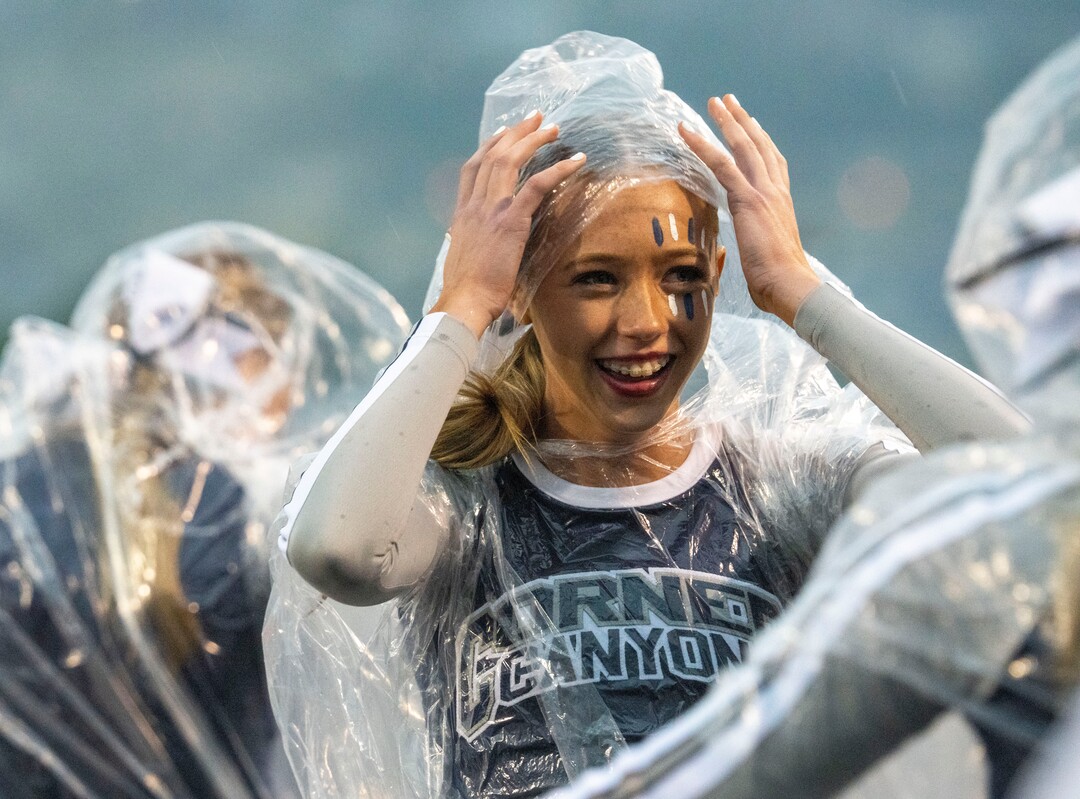 (Rick Egan | The Salt Lake Tribune) A Corner Canyon cheer leader tries watch the game through the wind and the rain, in prep football action between Corner Canyon Chargers and the East Leopards, on Saturday, Aug. 21, 2021.