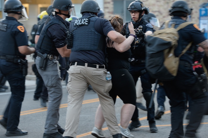 (Francisco Kjolseth  |  The Salt Lake Tribune) A woman is arrested as police line up to enforce a mandatory curfew in Salt Lake City on Monday, June 1, 2020, following violence and unrest over the weekend due to the death of George Floyd by police.