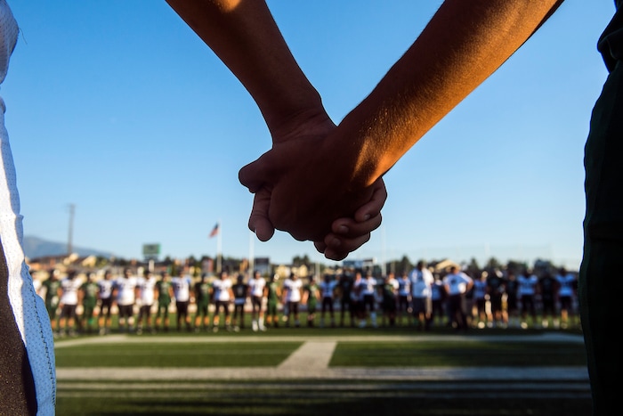 (Chris Detrick  |  The Salt Lake Tribune)    Members of the Hillcrest and Highland football teams hold hands during a remembrance for Hillcrest football coach Cazzie Brown before the game at Hillcrest High School Friday, September 1, 2017. Cazzie Brown passed away Sunday night after spending four days in the hospital. According to a family representative, Brown was brought to the emergency room Wednesday for complications with his thyroid. The doctors found that he had contracted meningitis, and later received a preliminary positive after being tested for West Nile virus. 