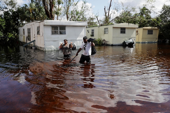 Angelina Ventura, left, and Jose Gonzalez retrieve belongings from their flooded home in the wake of Hurricane Irma in Bonita Springs, Fla., Tuesday, Sept. 12, 2017. (AP Photo/David Goldman)