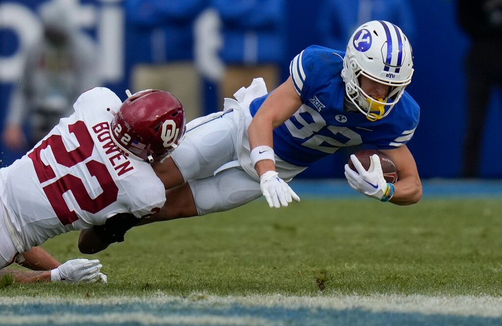 (Bethany Baker | The Salt Lake Tribune) Oklahoma Sooners defensive back Peyton Bowen (22) tackles Brigham Young Cougars wide receiver Parker Kingston (82) at LaVell Edwards Stadium in Provo on Saturday, Nov. 18, 2023.