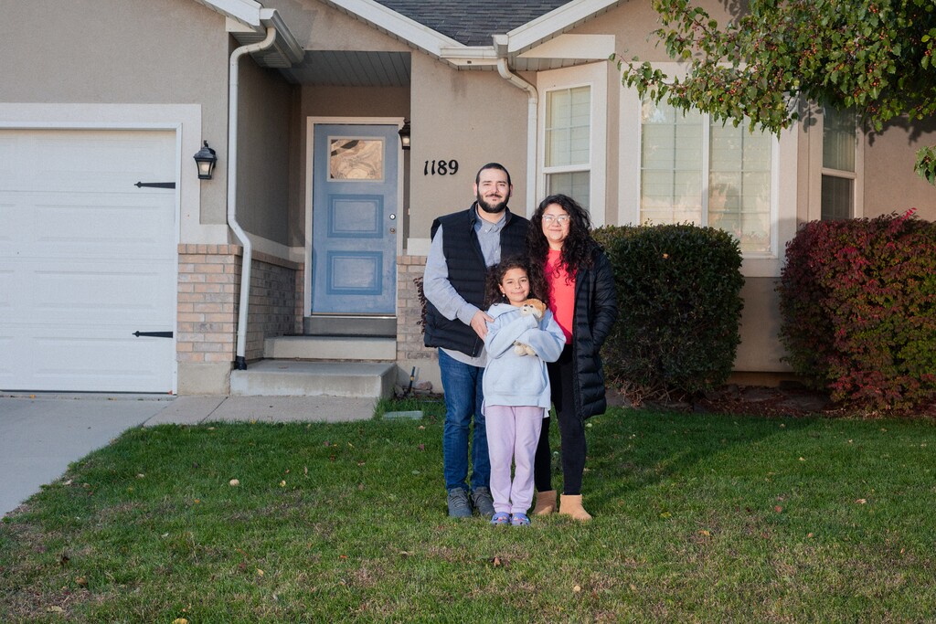 (Angie Smith | The New York Times) Sam McMullin with his wife, Javiera, and daughter, Mila in front of their home in American Fork, Utah, Oct. 27, 2025. With decades of equity and their children facing a tough housing market, older homeowners are helping their children buy their first homes.
