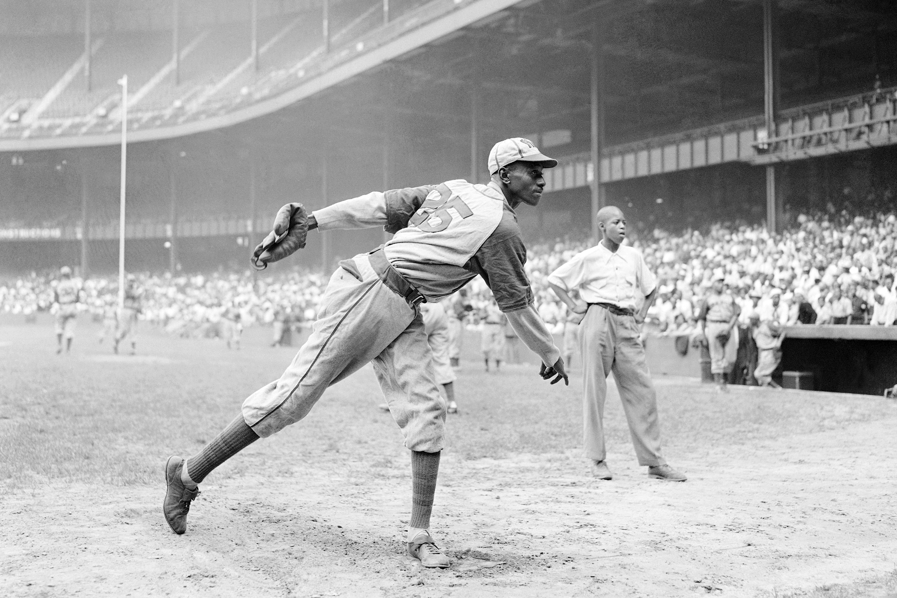 FILE - In this Aug. 2, 1942, file photo, Kansas City Monarchs pitcher Leroy Satchel Paige warms up at New York's Yankee Stadium before a Negro League game between the Monarchs and the New York Cuban Stars. Major League Baseball has reclassified the Negro Leagues as a major league and will count the statistics and records of its 3,400 players as part of its history. The league said Wednesday, Dec. 16, 2020, it was "correcting a longtime oversight in the game's history" by elevating the Negro Leagues on the centennial of its founding. (AP Photo/Matty Zimmerman, File)