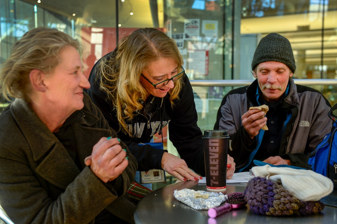 (Leah Hogsten  |  The Salt Lake Tribune)  Katherine Barrett, 54, and her husband Ron Barrett, 55, share a laugh with Rhonda Robison, center, a homeless outreach program worker for the Volunteers of America stationed at the Salt Lake Library, as Robison writes out a clothing voucher for the two. The Barretts, who are homeless, have three months to find housing through a Shelter Plus Care housing voucher through the Salt Lake City Housing Authority.