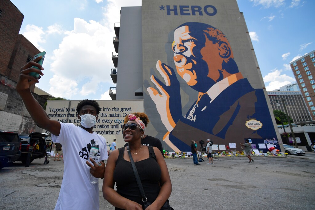 (Mike Stewart | AP photo)
People gather at a make-shift memorial near the home of Rep. John Lewis, D-Ga., Sunday, July 19, 2020, in Atlanta. Lewis, who died Friday at age 80, was the youngest and last survivor of the Big Six civil rights activists who organized the 1963 March on Washington, and spoke shortly before the group's leader, Rev. Martin Luther King Jr., gave his "I Have a Dream" speech to a vast sea of people.