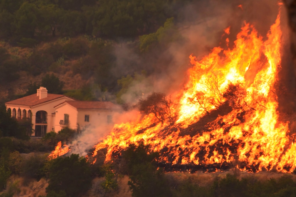 FILE - In this Thursday, Dec. 14, 2017, file photo provided by the Santa Barbara County Fire Department, flames from a back firing operation underway rise behind a home off Ladera Lane near Bella Vista Drive in Santa Barbara, Calif. Crews battling Southern California's enormous wildfire are struggling to widen and extend firebreaks before the return of winds Wednesday evening, Dec. 20, 2017, that could once again drive the flames out of control. (Mike Eliason/Santa Barbara County Fire Department via AP, File)
