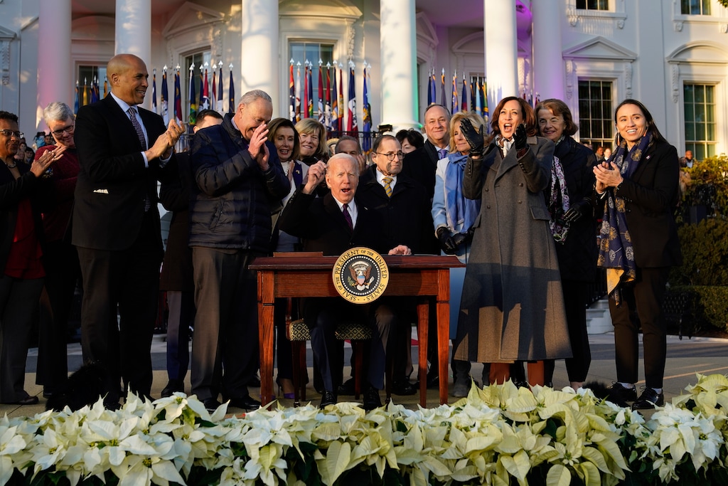 (Patrick Semansky | AP) President Joe Biden raises his pen and reacts to applause after signing the Respect for Marriage Act, Tuesday, Dec. 13, 2022, on the South Lawn of the White House in Washington.