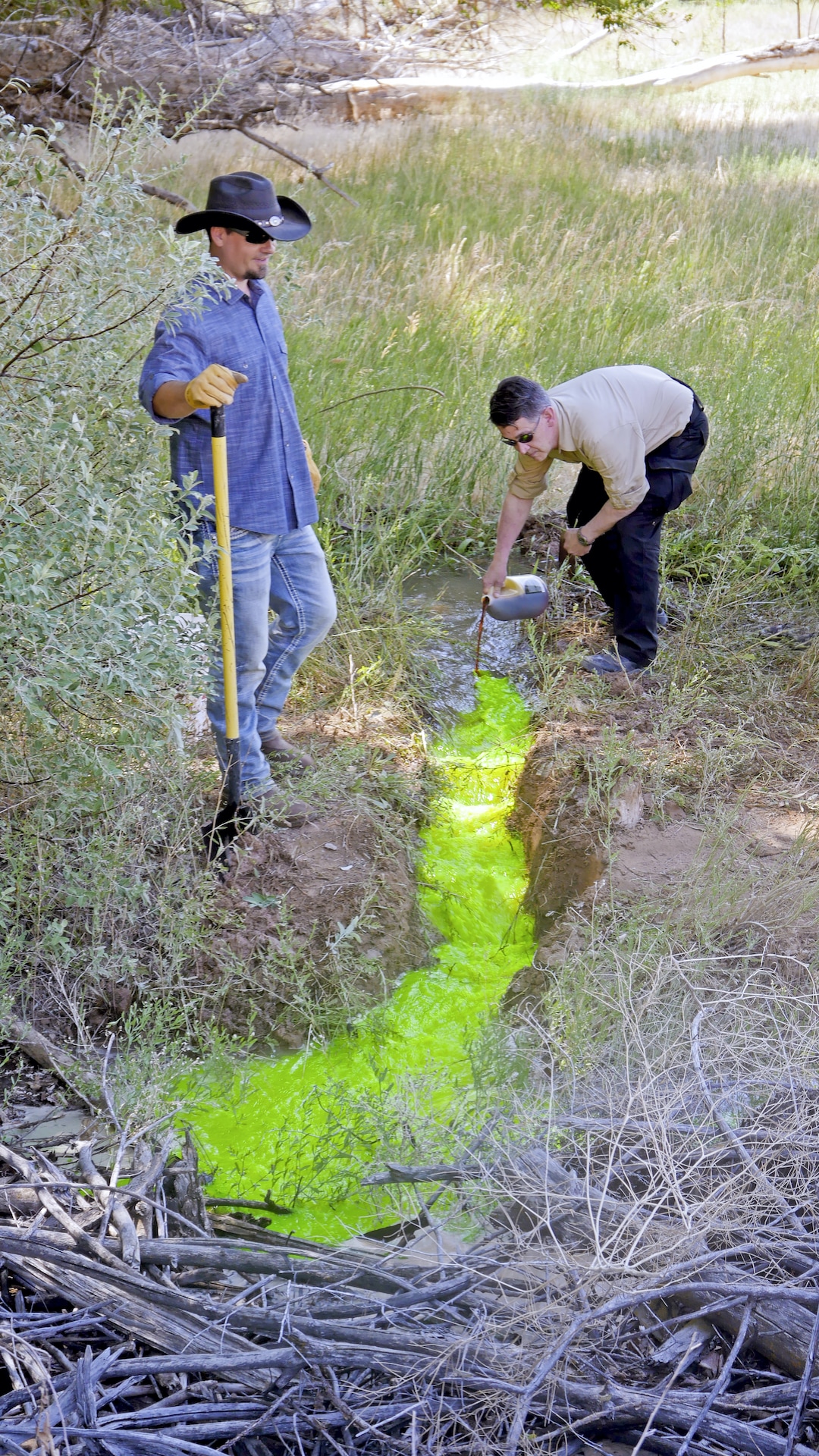 (History Channel) Thomas Winterton, left, and Erik Bard pour environmentally friendly green dye into water on the ranch for an experiment, in a moment from History's series "The Secret of Skinwalker Ranch."