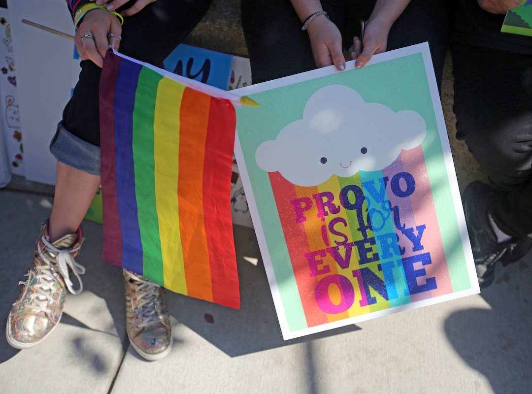 People hold signs during a news conference to discuss the America's Freedom Festival's decision Thursday, June 14, 2018, in Provo, Utah. LGBT groups that were denied requests to participate in a July 4 parade that is part of America's Freedom Festival in Provo spoke out Thursday about being rejected even after festival organizer and Provo city officials signed a nondiscrimination deal. (AP Photo/Rick Bowmer)