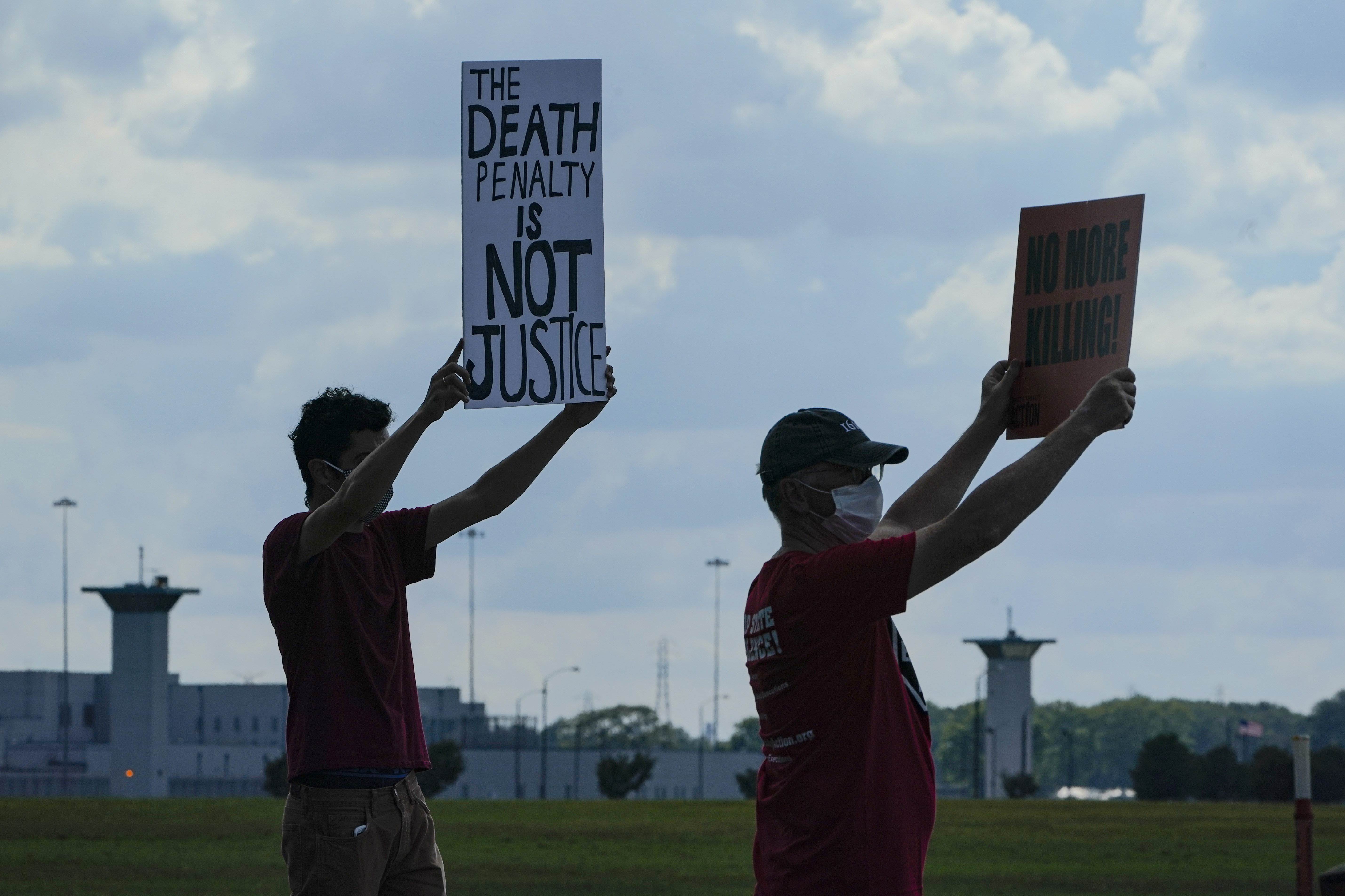 (Michael Conroy | AP) Death penalty protestors hold up signs across the street from the federal prison complex in Terre Haute, Ind., Wednesday, Aug. 26, 2020. Lezmond Mitchell, the only Native American on federal death row, was executed Wednesday for the slayings of a 9-year-old and her grandmother nearly two decades ago.