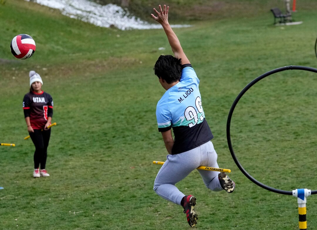 (Francisco Kjolseth | The Salt Lake Tribune) Michael Liou leaps into the air to defend the hoops while playing Quidditch at Reservoir Park in Salt Lake City on Wednesday, April 13, 2022. Based off the Harry Potter books, Quidditch requires each player to keep a broom stick between their legs at all times as three chasers, two beaters, a keeper and a seeker work to score points by getting the quaffle (a volleyball) through a hoop. 