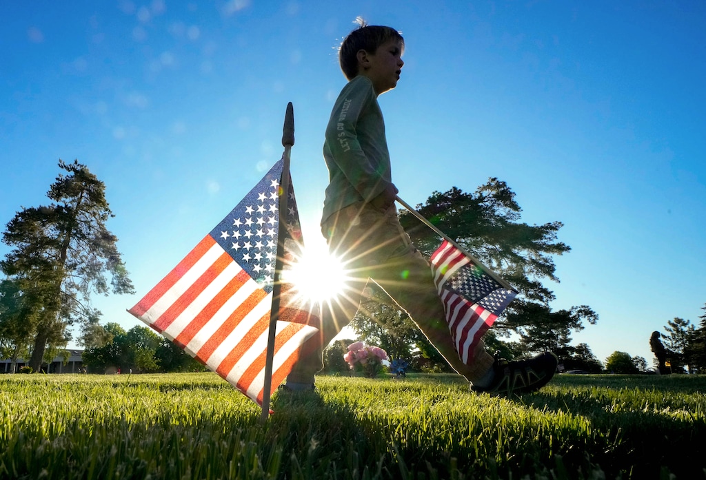 (Francisco Kjolseth | The Salt Lake Tribune) Max Peterson, 8, joins his family and more than 200 youth volunteers from around the Salt Lake Valley to help honor veterans for Memorial Day by placing 3,000 American flags on the graves of service men and women at Larkin Sunset Gardens Cemetery in Sandy on Thursday, May 23, 2024.