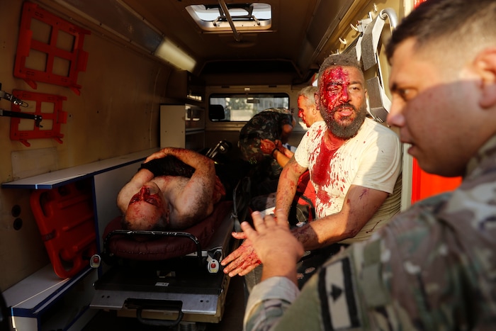 A Lebanese soldier, right, checks injured men who sit inside an umbulance at the explosion scene that hit the seaport of Beirut, Lebanon, Tuesday, Aug. 4, 2020. Massive explosions rocked downtown Beirut on Tuesday, flattening much of the port, damaging buildings and blowing out windows and doors as a giant mushroom cloud rose above the capital.  (AP Photo/Hussein Malla)