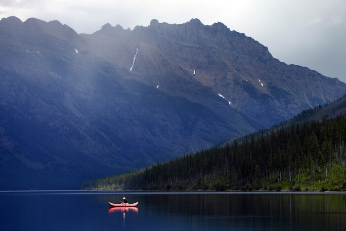 FILE - In this Sunday, July 10, 2016 file photo, a lone fisherman glides along on Kintla Lake in North Glacier National Park, Mont. Hawaii residents and an organization representing federal workers filed a lawsuit against the Federal Aviation Administration on Wednesday, Oct. 4, 2017 seeking to force it to do something about tour helicopters buzzing around seven national parks across the country. (Brenda Ahearn/The Daily Inter Lake via AP, File)