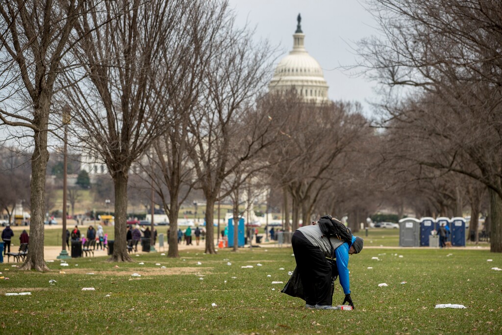 FILE - In this Dec. 25, 2018, file photo, the Capitol building is visible as a man picks up garbage during a partial government shutdown on the National Mall in Washington. No city experiences a shutdown quite like Washington. Besides the economic impact, a shutdown warps the nation’s capital on a cultural, recreational and logistical level. (AP Photo/Andrew Harnik, File)