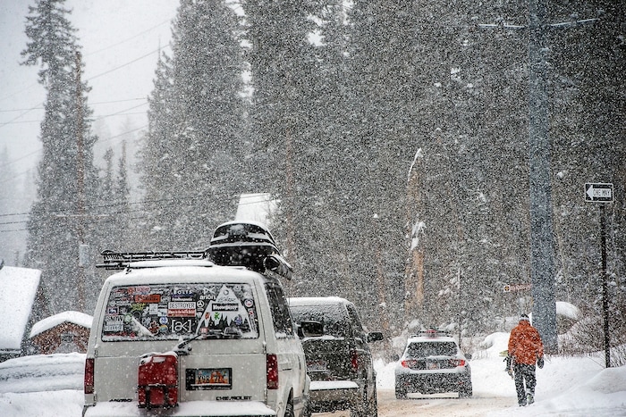 (Chris Detrick | The Salt Lake Tribune) A snowboarder walks along South Brighton Loop Road in Brighton Saturday, December 23, 2017.