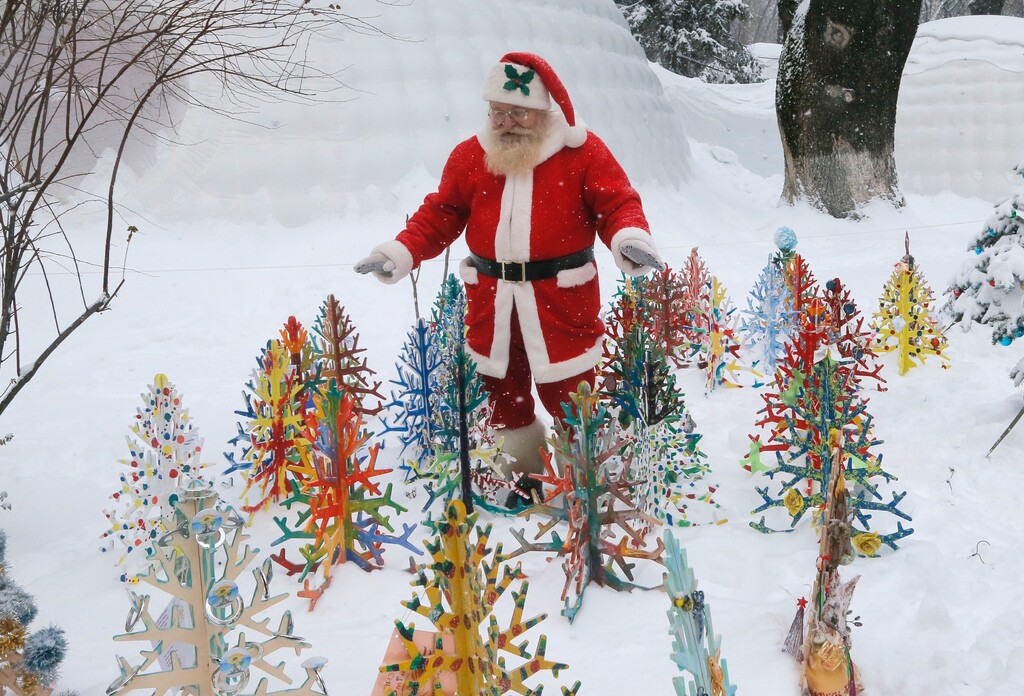 A man dressed as Santa Claus walks in deep snow looking at small artificial Christmas trees in a snowy city park in Kiev, Ukraine, Tuesday, Jan. 10 2017. The temperature in Kiev is -6 degrees Centigrade (22 degrees Fahrenheit). (AP Photos/Efrem Lukatsky)