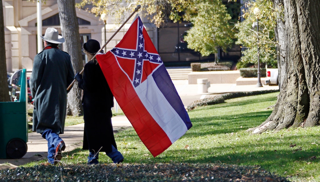 FILE - In this Jan. 19, 2016 file photo, a couple leaves the grounds of the state Capitol in Jackson, Miss., after participating in a rally in support of keeping the Confederate battle emblem on the state flag. Attorneys say in written arguments to U.S. Supreme Court that the Confederate battle emblem on the Mississippi flag is “an official endorsement of white supremacy” and lower courts were wrong to block a lawsuit challenging the flag. The arguments were made in papers filed Friday, Oct. 27, 2017,  by lawyers for Carlos Moore, an African-American attorney who sued the state in 2016 seeking to have the flag declared an unconstitutional relic of slavery.  (AP Photo/Rogelio V. Solis, File)