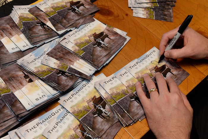(Francisco Kjolseth | The Salt Lake Tribune) The Piano Guys prepare for an upcoming show by signing CDs while gathered together at their home studio in Sandy recently.