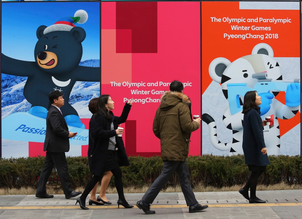 People pass by posters showing the 2018 Pyeongchang Winter Olympic mascots in Seoul, South Korea, Wednesday, Jan. 17, 2018. North Korea plans to send a 230-member cheering squad to South Korea as part of its delegation to next month's Winter Olympics, Seoul officials said Wednesday, the latest in a series of conciliatory gestures the North has abruptly taken recently following a year of heightened nuclear tension. (AP Photo/Ahn Young-joon)
