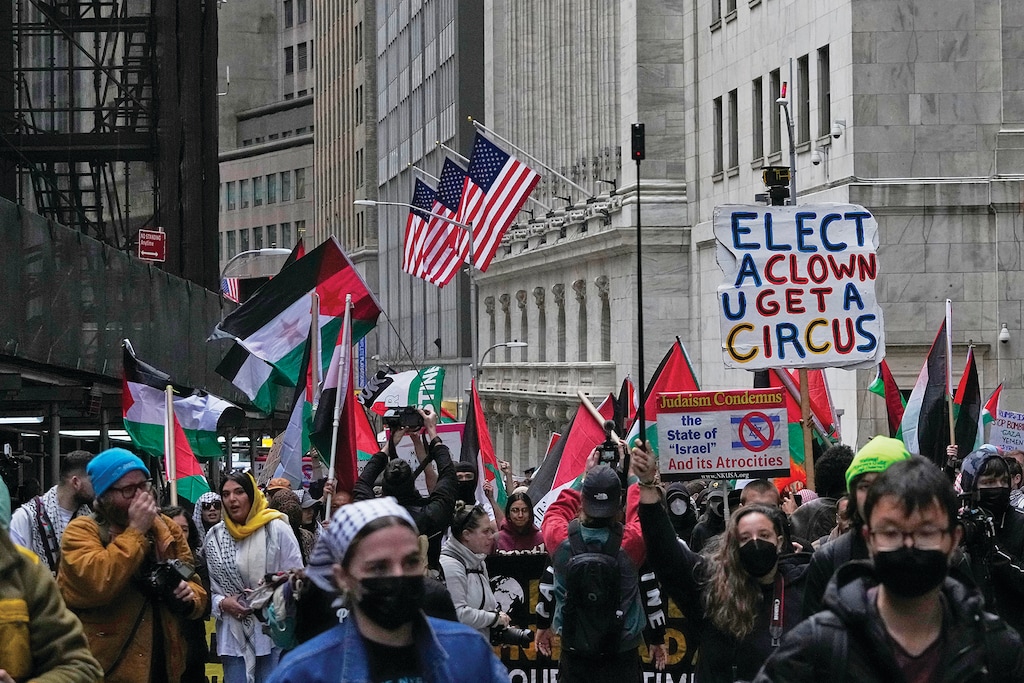 Protestors pass the New York Stock Exchange Wednesday, March 19, 2025, in New York. (AP Photo/Frank Franklin II)