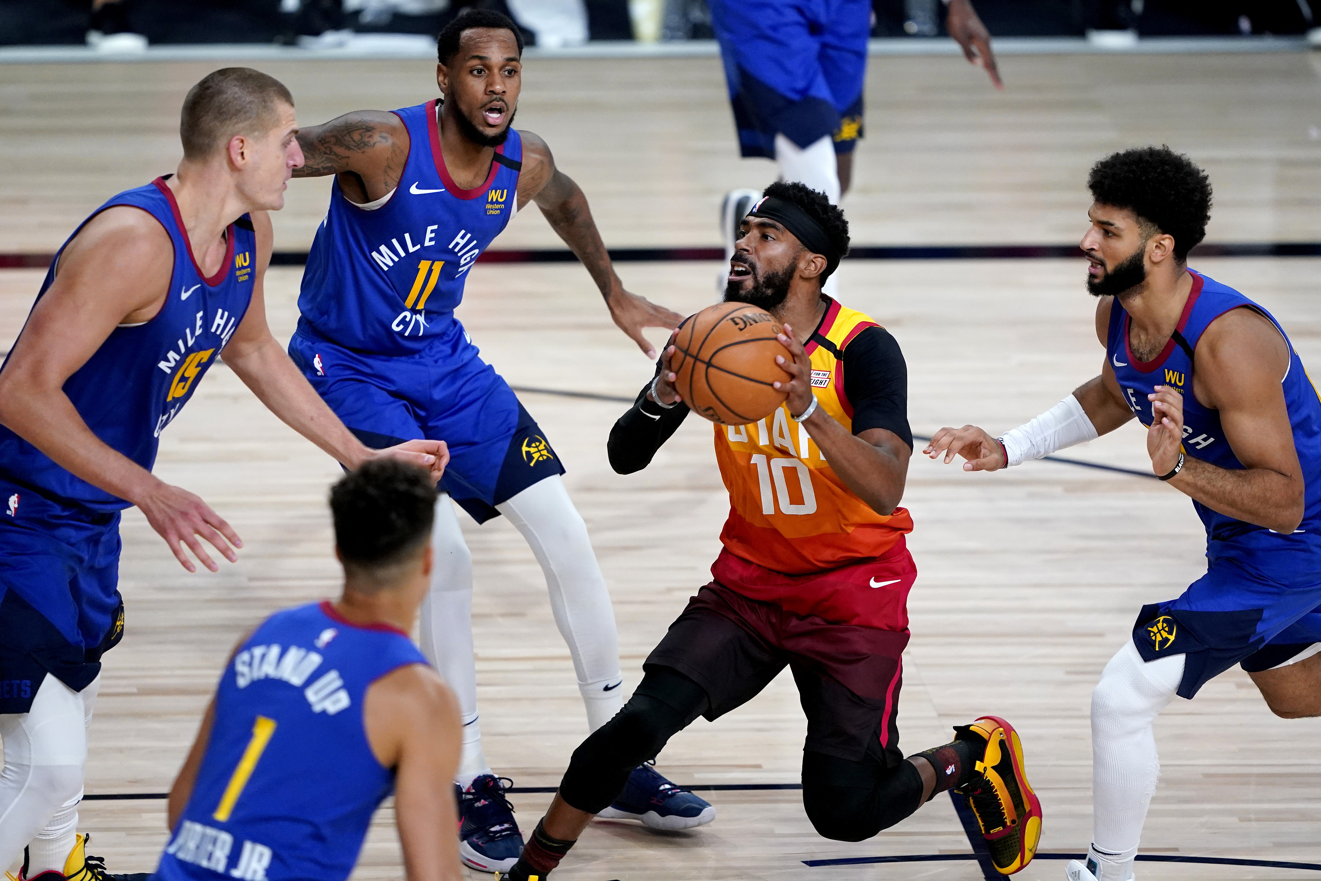Utah Jazz's Mike Conley (10) drives as Denver Nuggets' Monte Morris (11), Nikola Jokic (15), Michael Porter Jr. (1) and Jamal Murray, right, defend during the first half of an NBA basketball first round playoff game Friday, Aug. 21, 2020, in Lake Buena Vista, Fla. (AP Photo/Ashley Landis, Pool)