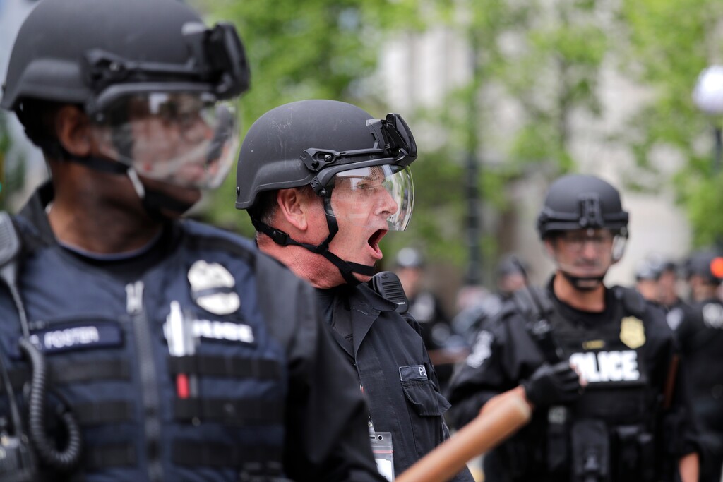 (Elaine Thompson | AP file photo)  A Seattle police officer yells out orders at Seattle City Hall as protesters march toward them in Seattle on June 3, 2020.