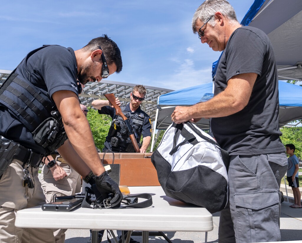 (Leah Hogsten | The Salt Lake Tribune) Paul Mazzie, right, turns in his father-in-law's Armalite AR-18, Saturday, June 11, 2022. In an effort to get guns off the streets, Utahns were encouraged to turn in their firearms during Saturday's gun buyback event at the Salt Lake City Police Department following a series of mass shootings across the U.S. in recent weeks.