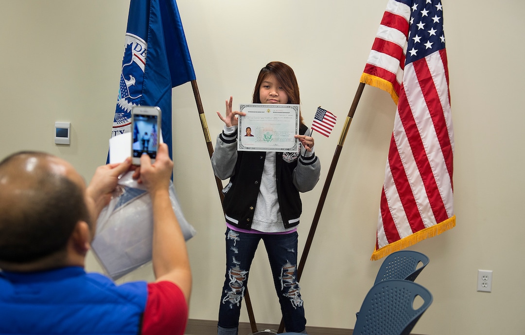 (Scott Sommerdorf   |  The Salt Lake Tribune)   New citizen Diana Vo has her photo taken by her father Don Vo, after a ceremony in recognition of children who have obtained citizenship through their parents, Thursday, December 28, 2017. The Vo family emigrated from Vietnam. Some were adopted by U.S. citizen parents; others derived citizenship when their immigrant parents became naturalized citizens.