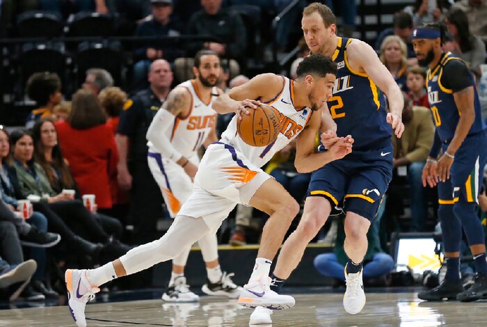 Utah Jazz guard Joe Ingles (2) guards against Phoenix Suns guard Devin Booker (1) who drives with the ball in the first half during an NBA basketball game Monday, Feb. 24, 2020, in Salt Lake City. (AP Photo/Rick Bowmer)