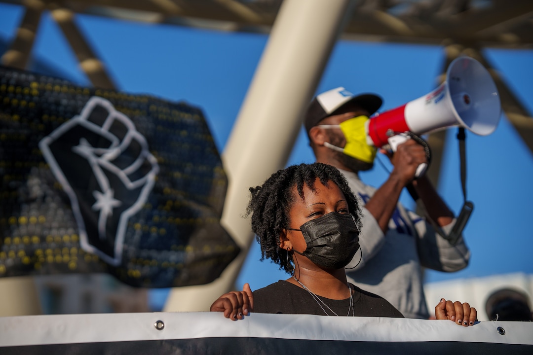 (Trent Nelson  |  The Salt Lake Tribune) Mihiret Burt holds a banner while Mario Mathis speaks at rally at the Public Safety Building in Salt Lake City on Tuesday, April 20, 2021 to mark the conviction of Derek Chauvin for the murder of George Floyd.
