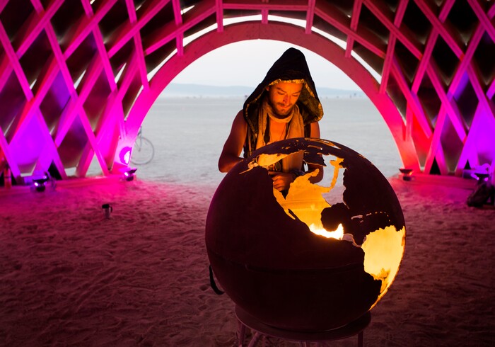 (Rick Egan  |  The Salt Lake Tribune)  Michael Talavera, of Austin  TX, checks out a fire globe in the Cosmic Connection by George Neil and the Quark Collective, glows in the evening, during Burning Man.  Thursday, August 31, 2017.