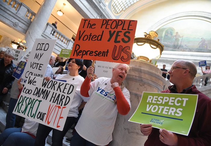 (Francisco Kjolseth  |  The Salt Lake Tribune)  Tiffany Malo, Pam Harrison and John Armstrong, from left, join over 300 demonstrators as they fill the Capitol rotunda on Monday, Jan, 28, 2019, on the first day of the Legislative session to rally in support of protecting Proposition 3, the Medicaid Expansion law recently passed by voters.