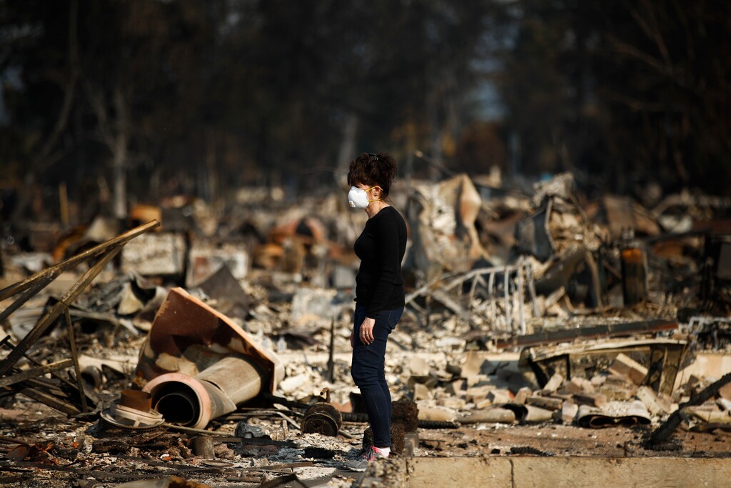 Karen Curzon stands in what remains of her home, which was destroyed by a wildfire in the Coffey Park neighborhood, Sunday, Oct. 15, 2017, in Santa Rosa, Calif. "We are going to rebound, rebuild and get this community back," said Curzon. (AP Photo/Jae C. Hong)