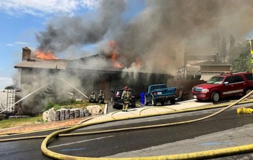 (Centerville Police Department) Firefighters battle a blaze started by a 37-year-old man who police said attacked three of the home's residents during a home invasion, then set the house on fire on Thursday, July 21, 2022.