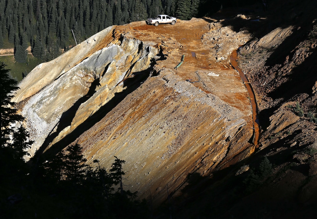 (Brennan Linsley | The Associated Press) In this Aug. 13, 2015 file photo, wastewater flows down a trough, right, from the site of the blowout at the Gold King mine which triggered a major spill of toxic wastewater, outside Silverton, Colo. Crumbling mine tunnels awash with polluted waters perforate the Colorado mountains, and scientists may one day send robots creeping through the pitch-black passages to study the mysterious currents that sometimes burst to the surface with devastating effects.