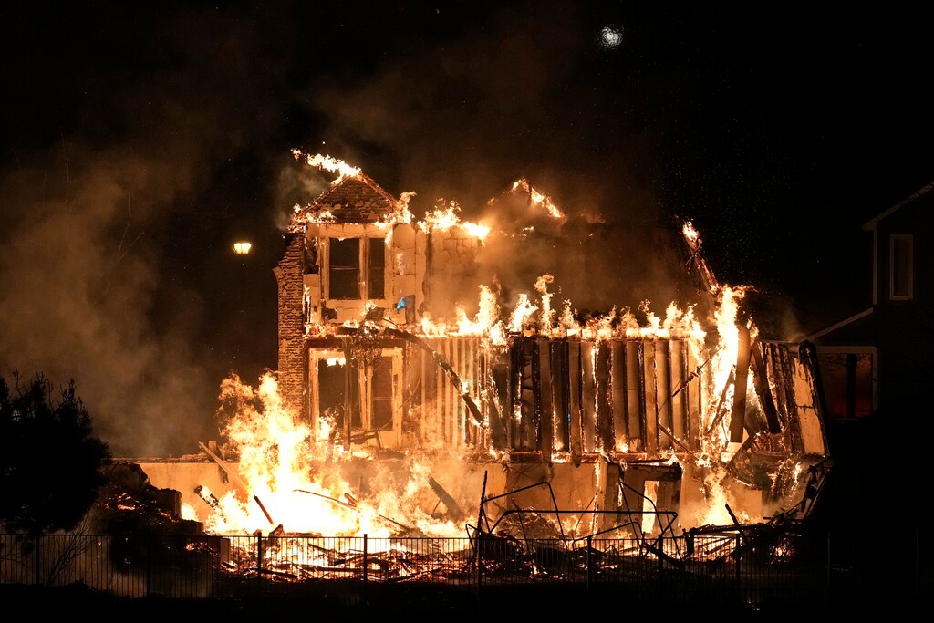 (David Zalubowski | AP) Homes burn as a wildfire rips through a development near Rock Creek Village, Thursday, Dec. 30, 2021, near Broomfield, Colo. Just over a year after the most destructive wildfire burned in Colorado's history, a bill is being introduced in the state's legislature to create a $2-million pilot program to use cameras likely equipped with artificial intelligence technology in high-risk areas to help identify fires before they can burn out of control.