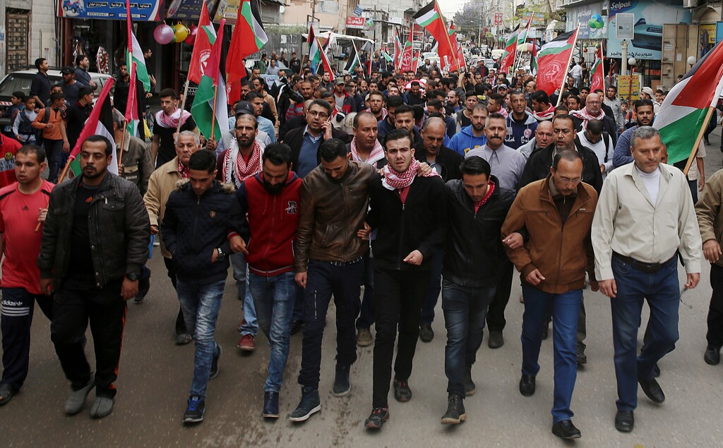 Mourners wave flags while the body of Palestinian journalist Ahmed Abu Hussein, who died after being shot by Israeli troops while covering a border protest, is carried during his funeral in the Jebaliya refugee camp, Gaza Strip, Thursday, April 26, 2018. (AP Photo/Adel Hana)