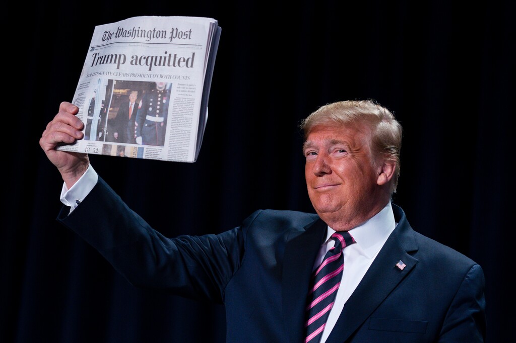 (Evan Vucci | AP)  President Donald Trump holds up a newspaper with the headline that reads "Trump acquitted" during the 68th annual National Prayer Breakfast, at the Washington Hilton, Thursday, Feb. 6, 2020, in Washington.