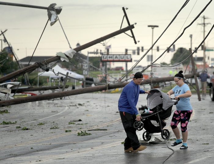 (Charlie Riedel | AP) Jessica Rodgers and a neighbor Ray Arellana carry a stroller carrying Rodgers' sister Sophia Rodgers over downed power lines as they head to Rodgers' mother's apartment to check on damage Thursday, May 23, 2019, after a tornado tore though Jefferson City, Mo. late Wednesday.