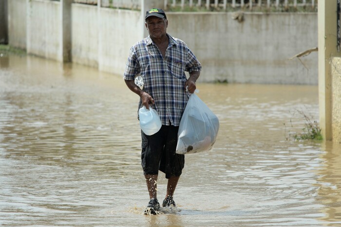 A resident carries supplies in a flooded road after the passing of Hurricane Maria, in Toa Baja, Puerto Rico, Friday, September 22, 2017. Because of the heavy rains brought by Maria, thousands of people were evacuated from Toa Baja after the municipal government opened the gates of the Rio La Plata Dam. (AP Photo/Carlos Giusti)