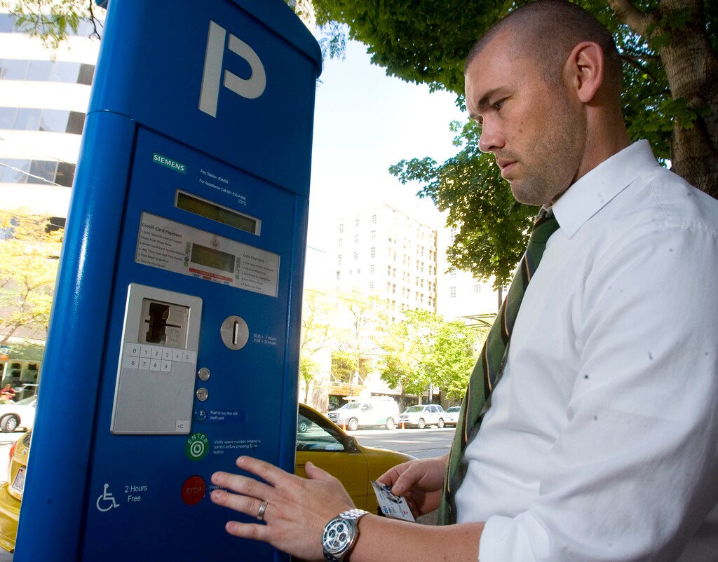 (Tribune File Photo) Chad Golsan, of Salt Lake City, goes through the steps to pay for parking at a parking kiosk on Main Street, August 21, 2013. After a moratorium on parking enforcement, Salt Lake City will begin once again imposing parking fees in downtown metered areas.