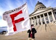 (Francisco Kjolseth | The Salt Lake Tribune) Herriman High social studies teacher Michael Stone holds a flag in strong bitter cold winds as educators, parents and other public school advocates rally on the steps of the Utah Capitol on Tuesday, Feb. 22, 2022. 