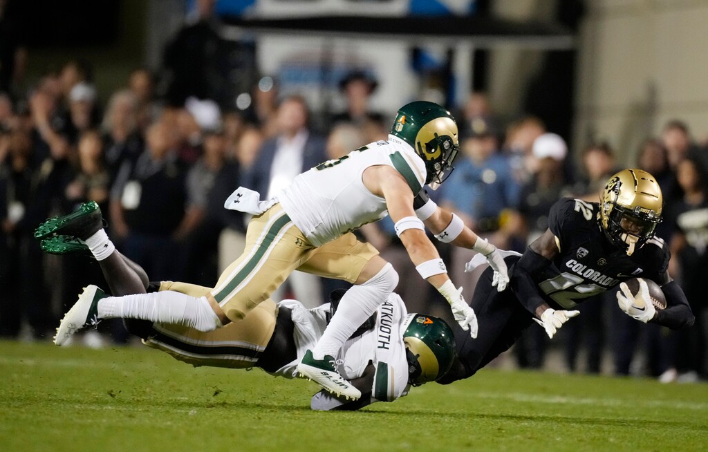 (David Zalubowski | AP) Colorado's Travis Hunter (12) is dragged down after a short gain by Colorado State defensive back Henry Blackburn, back left, and defensive back Ayden Hector during the first half of a game Saturday in Boulder, Colo.