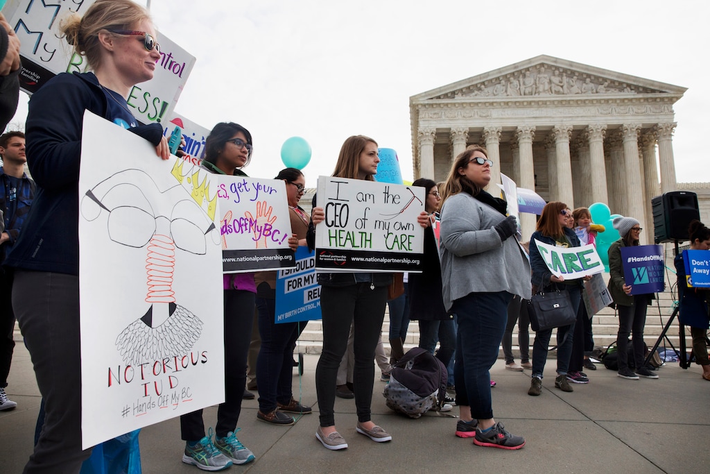 Kate Perelman of Silver Spring, Md., left, with Americans United for Separation of Church and State, holds a sign saying "Notorious IUD" as a play on words with the nickname for Supreme Court Justice Ruth Bader Ginsburg, as she, and others, rally in support of birth control access regardless of employer, Wednesday, March 23, 2016, outside the Supreme Court in Washington. The Supreme Court is taking up a challenge from faith-based groups that object to an Obama administration effort to ensure their employees and students can get cost-free birth control. (AP Photo/Jacquelyn Martin)